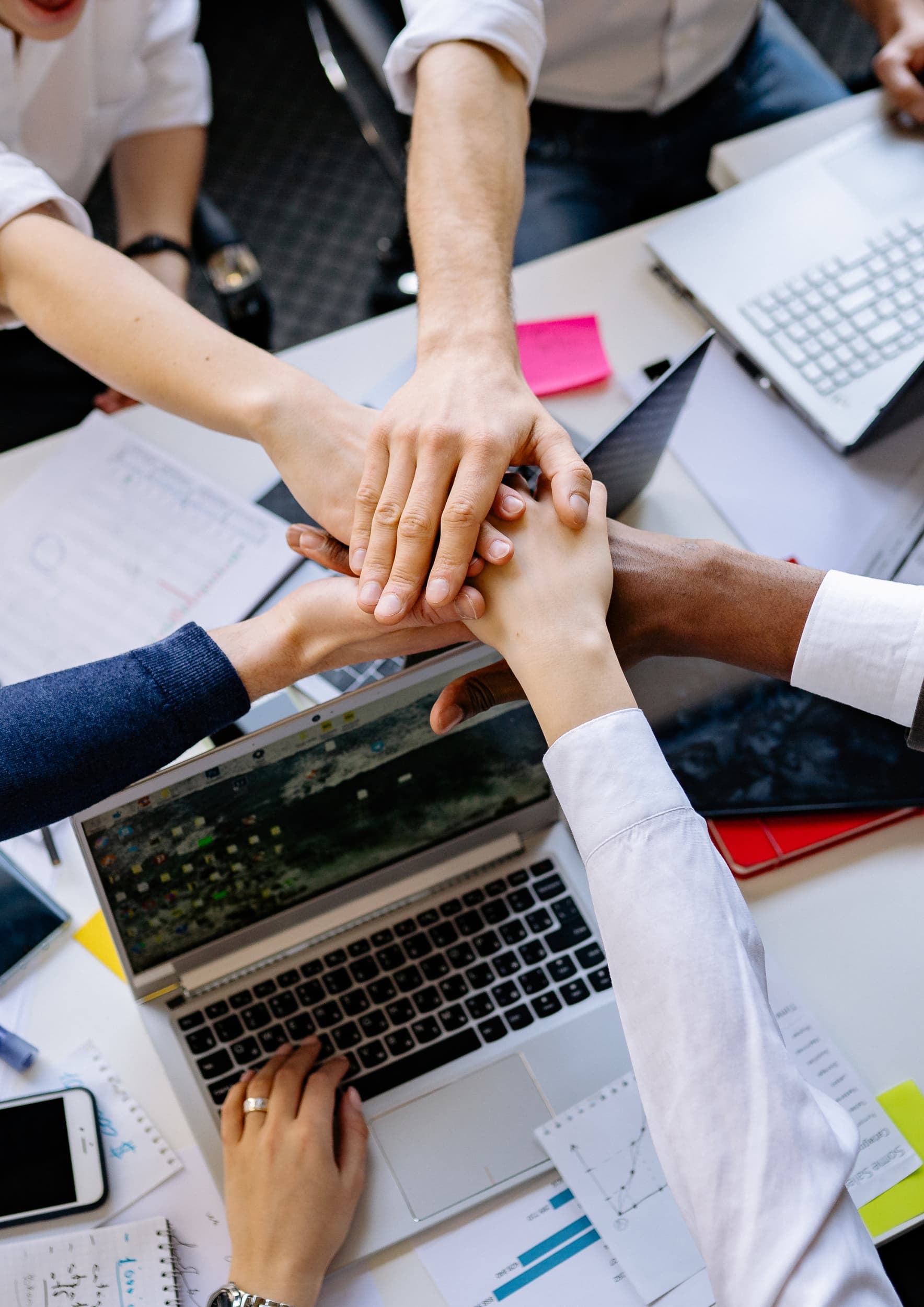 Équipe réunie autour d'une table de travail, mains posées les unes sur les autres